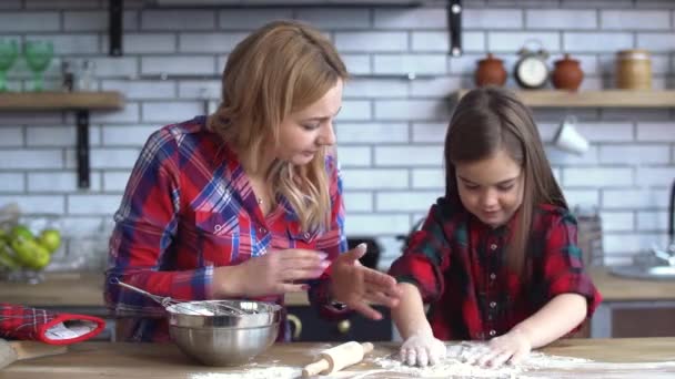 Beautiful young mother with blond long hair mixing in plate and small cute naughty girl play with flour on the kitchen table — Stock Video