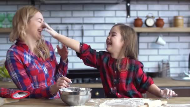 Gelukkig moeder met dochter spelen in keuken, klein meisje zetten bloem mamas gezicht — Stockvideo