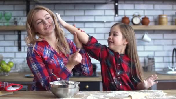 Carefree jovem mãe e filha brincando na cozinha cozinhar na mesa da cozinha. Mãe e criança se divertir juntos . — Vídeo de Stock