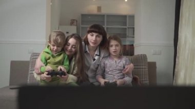 Mutlu aile dört üye video oyunu oynamak. İki küçük çocuk oyun çubukları tutun. Eğlenceli aile tatili.