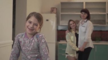 İki ablası kucaklayan arka plan üzerinde küçük kız gülümseyerek eğlenceli bir portresi. Aile ilişkileri