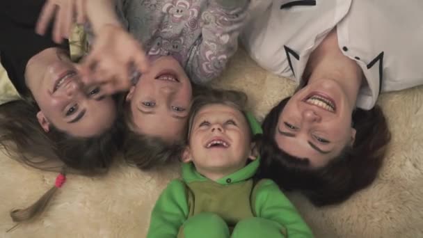 Portrait d'une famille souriante heureuse et agitant la main allongée sur un tapis moelleux par terre. Joyeuses vacances en famille . — Video