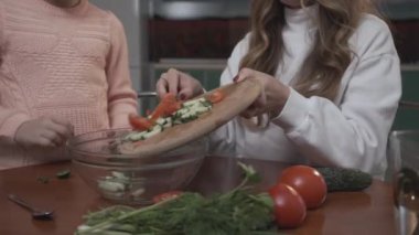 Genç kız eski kız coocking sebze salatası rahat mutfakta küçük bir masada oturup kahvaltı için yardımcı olur. Kız kardeş ilişkisi.