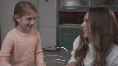 Küçük kız kardeşi yardımcı olur ablası coocking sebze salatası kahvaltı için. En büyük kız salatalık dilimleri ve Genç kız bir salata bir kaşık kullanarak bir tabak içinde karışımları. Kız kardeş ilişkisi.