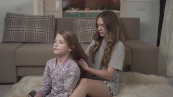 Older Sister Combing Hair Younger Girl Sitting Floor Fluffy Carpet — Stock Video