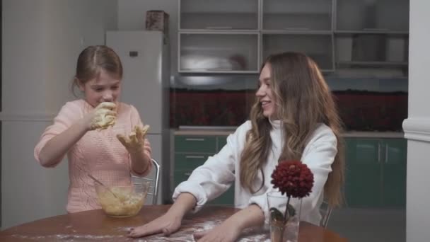 La niña está aprendiendo a cocinar en casa. El niño que se prepara tiene masa pegajosa en las manos — Vídeos de Stock