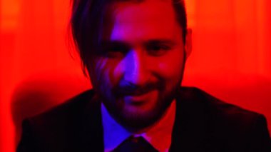 Kamera seyir sakallı gülümseyen adam portresi. Kırmızı ışıkta çekim