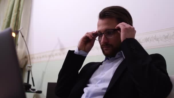 Όμορφος άνδρας με γυαλιά που λειτουργεί σε φορητό υπολογιστή στο σπίτι — Αρχείο Βίντεο