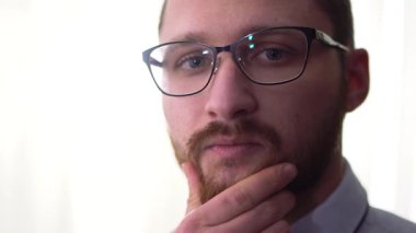 Gözlüklü bir beyaz arka plan yakın çekim izole dalgın yakışıklı sakallı işadamı portresi.
