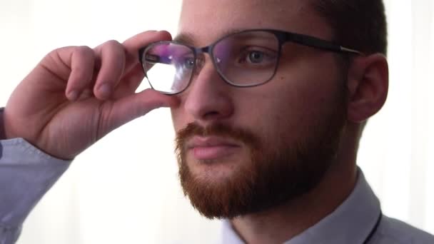 Retrato de um belo empresário barbudo tirando óculos isolados em um fundo branco close-up . — Vídeo de Stock