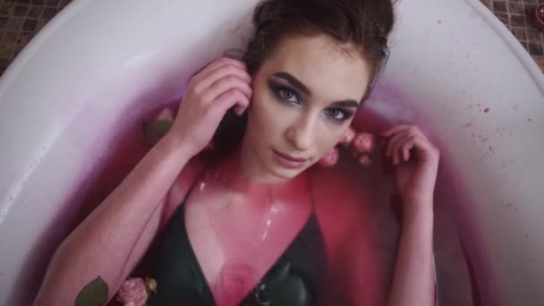 Mujer joven bastante tierna con brillante maquillaje relajante tomar un baño con rosas en el salón de spa. Linda chica disfrutando en el baño. Movimiento lento . — Vídeo de stock