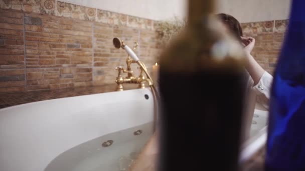 Deux bouteilles vides d'alcool sont sur le bord de la salle de bain fermer. Triste femme est assise dans le bain. Deux bouteilles au premier plan sur le bord du bain . — Video