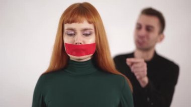 Sessiz agresif sinirli adam çığlık iken ve kadın bağırıyor bantlanmış ağzı olan genç kadın portresi.