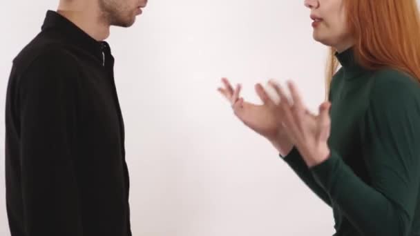 Upset woman yelling at young man, shaking waving hands and guy grabbed her arms and try to stop girl with long red hair and make her calm down. — Stock Video