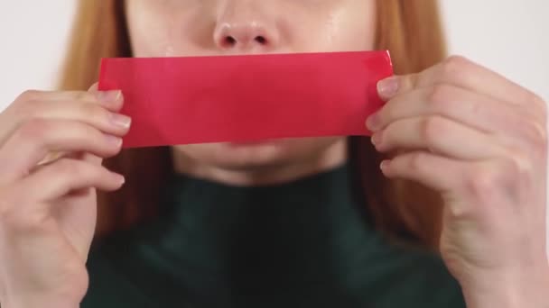 Young upset crying woman with long hair put red tape on her mouth with hands — Stock Video