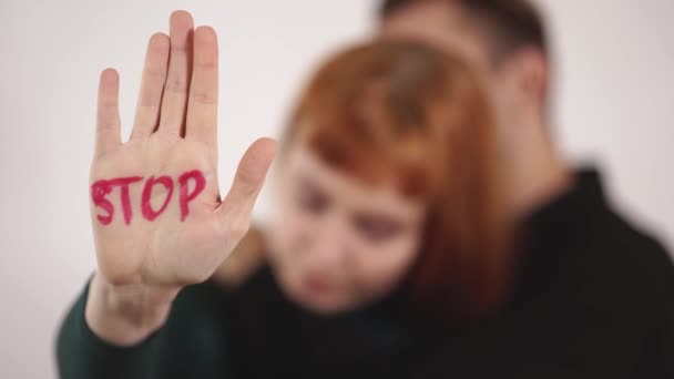 Silueta de pareja en fondo blanco, hombre abrazar a la mujer y acariciar su cabeza, mujer mostrando signo escrito en su mano "detener" la violencia — Vídeo de stock