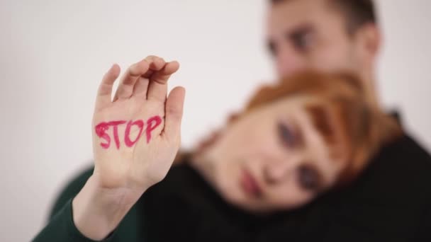 Çift arka planda beyaz adam silüeti kadın kucaklamak ve başını okşayın, Erkek yakın parmaklarını elini "Dur" violance yazılı işaretiyle — Stok video