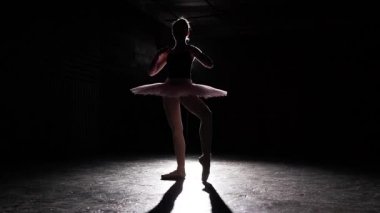 Siyah arka plan üzerine izole balerin silüeti. Genç balerin bale pratik ince. Balerin dansçı tutu ve pointe ayakkabı giyiyor. Kadın klasik bale pas gösterir. Ağır çekim.