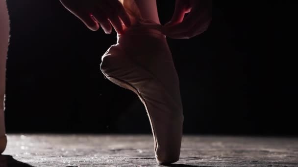 Close-up van een vrouwelijke handen koppelverkoop ballet schoenen geïsoleerd op zwarte achtergrond. Slow motion. — Stockvideo