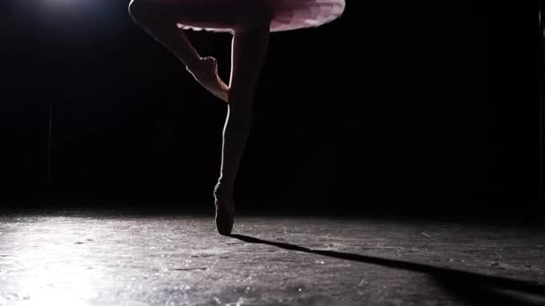 Ballerina pirouettes uitvoeren op een zwarte achtergrond in de studio. Vrouwelijke balletdanser tutu en pointe schoenen dragen. Slow motion. — Stockvideo