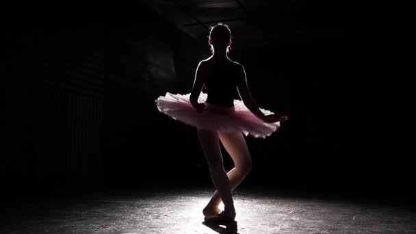 Krásnou siluetu mladých baletka na pointe boty na pozadí černé betonovou podlahu. Baletu. Krásnou štíhlou postavu baletku. Zpomalený pohyb.