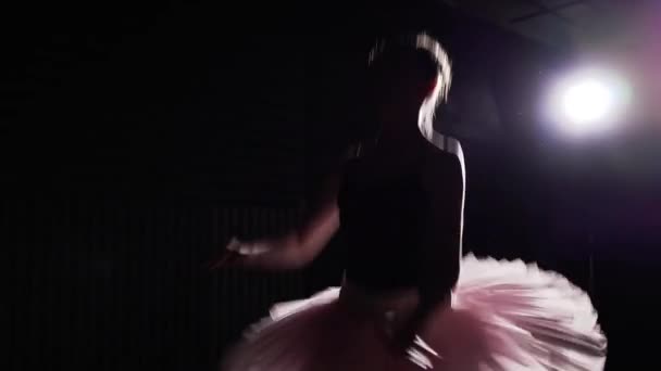 Jong en gracieuze ballerina dansen op haar pointe ballet schoenen in middelpunt van de belangstelling op een zwarte achtergrond in de studio... Vrouw toont pas van de klassieke ballet tutu en pointe schoenen dragen. Slow motion. — Stockvideo