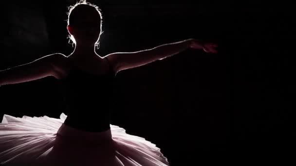 Graceful young flexible ballerina dancing on her pointe ballet shoes in spotlight on black background in studio. Ballet dancer shows classic ballet pas wearing tutu and pointe shoes. Slow motion. — Stock Video