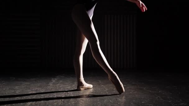 Професійна витончена гнучка балерина, що стоїть на взутті для балету в центрі уваги на чорному тлі в студії. Повільний рух . — стокове відео