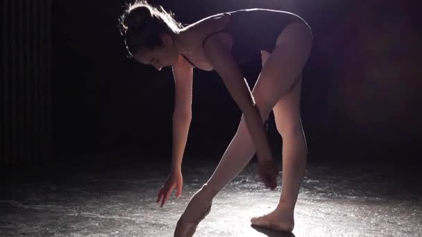 Hermosa bailarina joven en la oscuridad. Práctica de ballet en fondo negro. Hermosa figura delgada de bailarina de ballet — Vídeo de stock