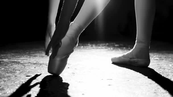 Hermosa bailarina joven de pie en sus zapatos de ballet puntiagudo en el centro de atención sobre fondo negro en el estudio. Práctica de ballet. Hermosas piernas finas y elegantes de bailarina de ballet. Tiro blanco y negro. Despacio. — Vídeos de Stock