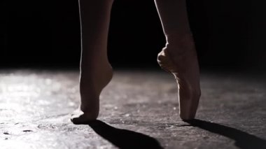 Kadın ince bacakları spot Studio siyah arka plan üzerine poz ayakta. Pointe ve başka bir ayakkabı ayaksız bir ayak