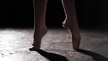 Spot Studio siyah arka plan üzerine poz ayakta kadın ince bacakları yukarı kapatın. Pointe ve başka bir ayakkabı ayaksız bir ayak.