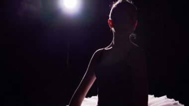 Genç ve güzel balerin spot Studio siyah arka plan üzerine onun pointe bale yerinde tutuyoruz. Kız tutu ve pointe ayakkabıları klasik bale pas gösterir.