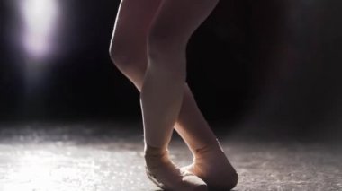 Zarif balerin pointe bale ayakkabılarını Studio siyah arka plan üzerine spot içinde dans. Kız pointe ayakkabıları klasik bale pas gösterir. Sadece kadın bacakları çerçevede görülebilir.