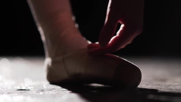 Closeup of a female hand touching ballet shoes isolated on black background. — Stock Video