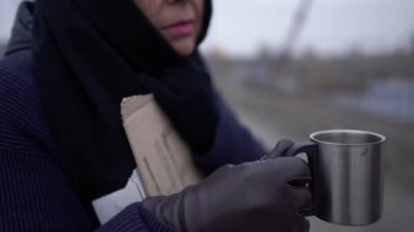 Yetişkin üzücü evsiz kadın kalın soğuk rüzgarlı gri hava asking için sadaka ve yardım ve birisi para koymak için durdu. Yakın çekim