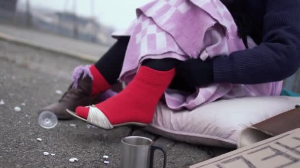 Dakloze vrouw waarderen de schoenen die gedragen op een dikke rode sok in de buitenlucht. — Stockvideo