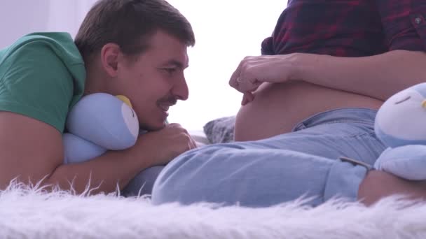 快乐的男人看着怀孕的妻子的肚子近距离微笑。夫妇模仿用手指的步 — 图库视频影像