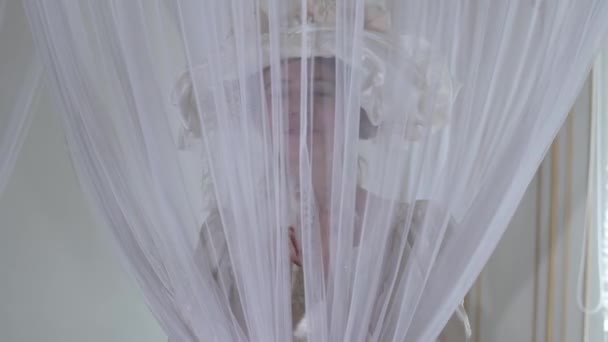 Vrouw in vintage bal kostuum en hoed kijkt door witte sluier, bedrijf veer ventilator in de hand dicht — Stockvideo