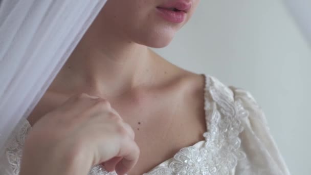 Junge Frauen Lippen und Schultern im Hochzeitskleid mit Stickerei auf weißem Hintergrund Halbgesicht echte Menschen Serie — Stockvideo