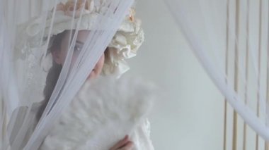 Mükemmel genç kadını çiçekler hayranları ile ipek şapkalı yüzüne peçe saklanıyor beyaz tüy Fanlı kapatın. Beyaz arka plan üzerinde gerçek insanlar serisi.