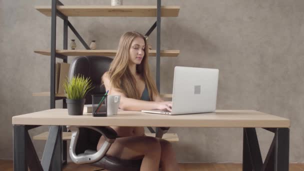 Stående ung söt flicka i underkläder som sitter i en svart skinnfåtölj bord att skriva på hennes laptop i moderna rum hemma. Fritid i vacker dam — Stockvideo