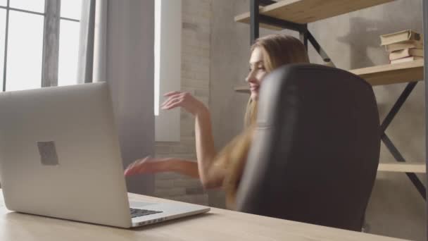 Stående ganska glädje flicka i underkläder som snurrar runt i läderfåtölj vid bord hemma. Vacker dam har goda nyheter. — Stockvideo