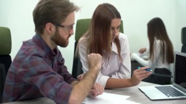 Adam ve genç kadın bir bilgisayarda bir projeyi tartışmak ve yorum ve yardım etmek için kendi meslektaşı diyorlar