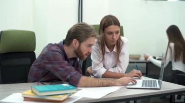 Gözlük ve rahat bir ekose gömlek ve bir güzel asistan beyaz gömlekli sakallı bir Yöneticisi ofiste o masada otururken bir laptop ekranında arıyoruz.