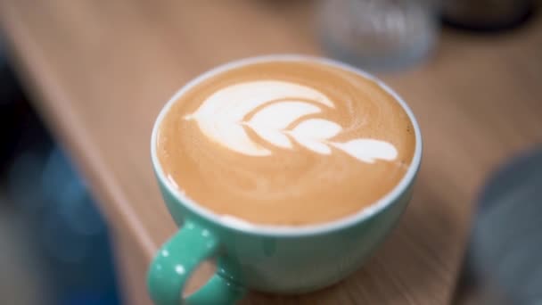 Cafea fierbinte preparată cu design de frunze într-o ceașcă turcoaz cu cremă și spumă perfectă. Closeup . — Videoclip de stoc