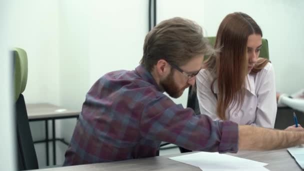 Бородатий менеджер в окулярах ділиться новою бізнес-стратегією зі своїм колегою, що показує на екрані ноутбука. Креативна ділова команда зустріч в сучасному офісі . — стокове відео