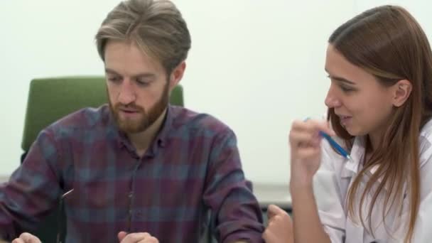 Hombre y mujer trabajan en una cómoda oficina moderna discutiendo de cerca. Proceso de trabajo — Vídeo de stock