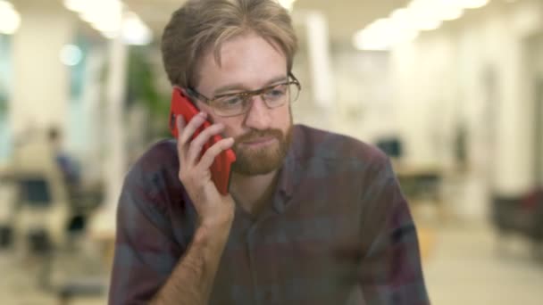 Glimlachende man met bril en casual plaid shirt praten op een mobiele telefoon met baard. — Stockvideo