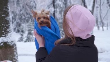 Genç kadın yükseltmek küçük köpek havlu açık havada kaplı kadar. Ağır çekim.